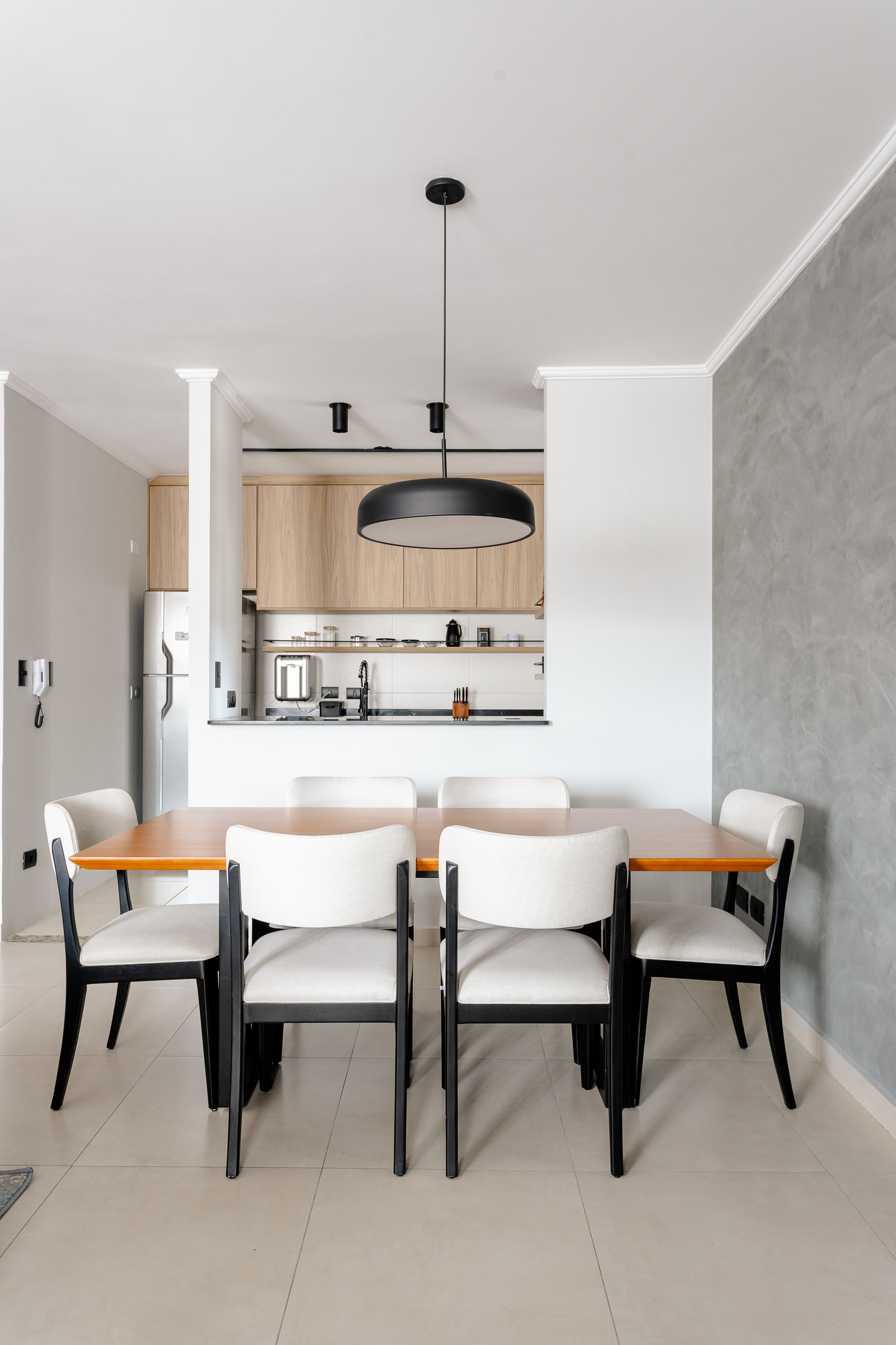 Sala de jantar com pendente industrial e mesa de madeira rústica em projeto contemporâneo